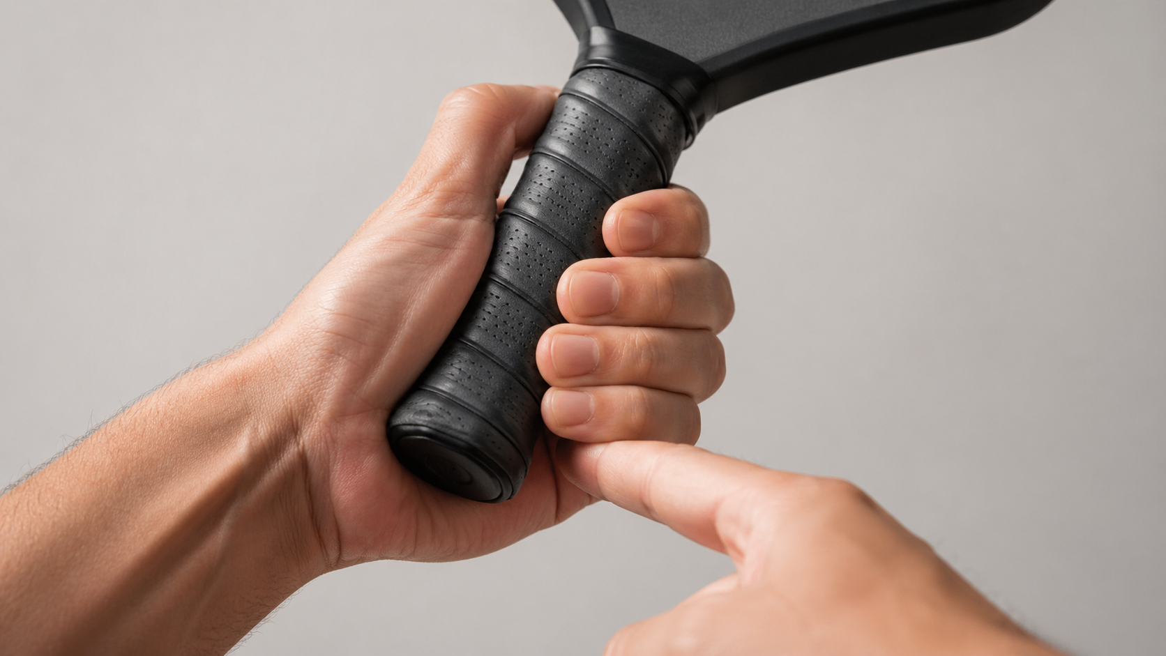 Close-up of a hand demonstrating the index finger gap test for pickleball paddle grip sizing