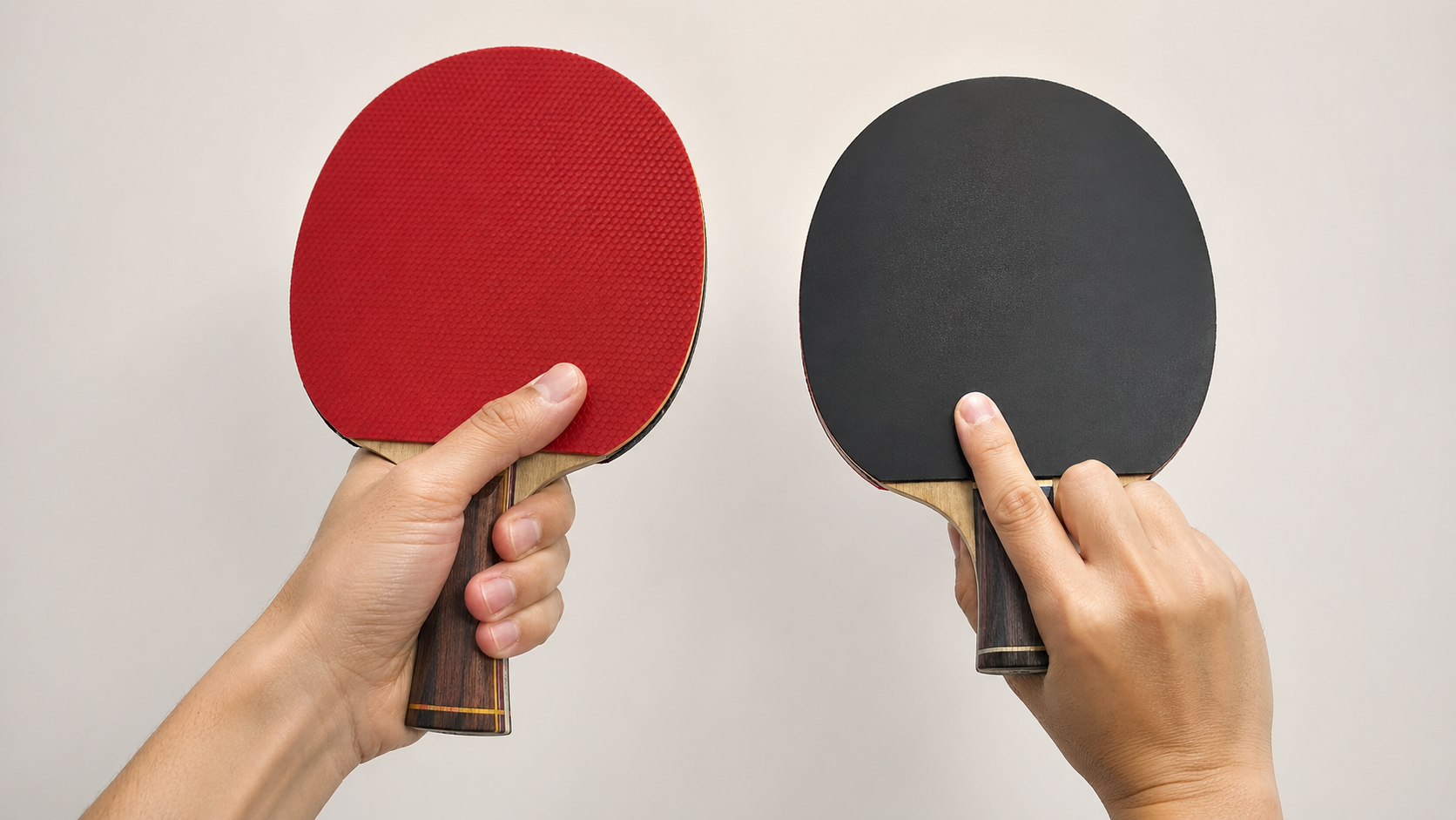 Two hands demonstrating table tennis grip styles — shakehand grip with flared handle on the left and Chinese penhold grip on the right, both holding rackets with red and black rubber