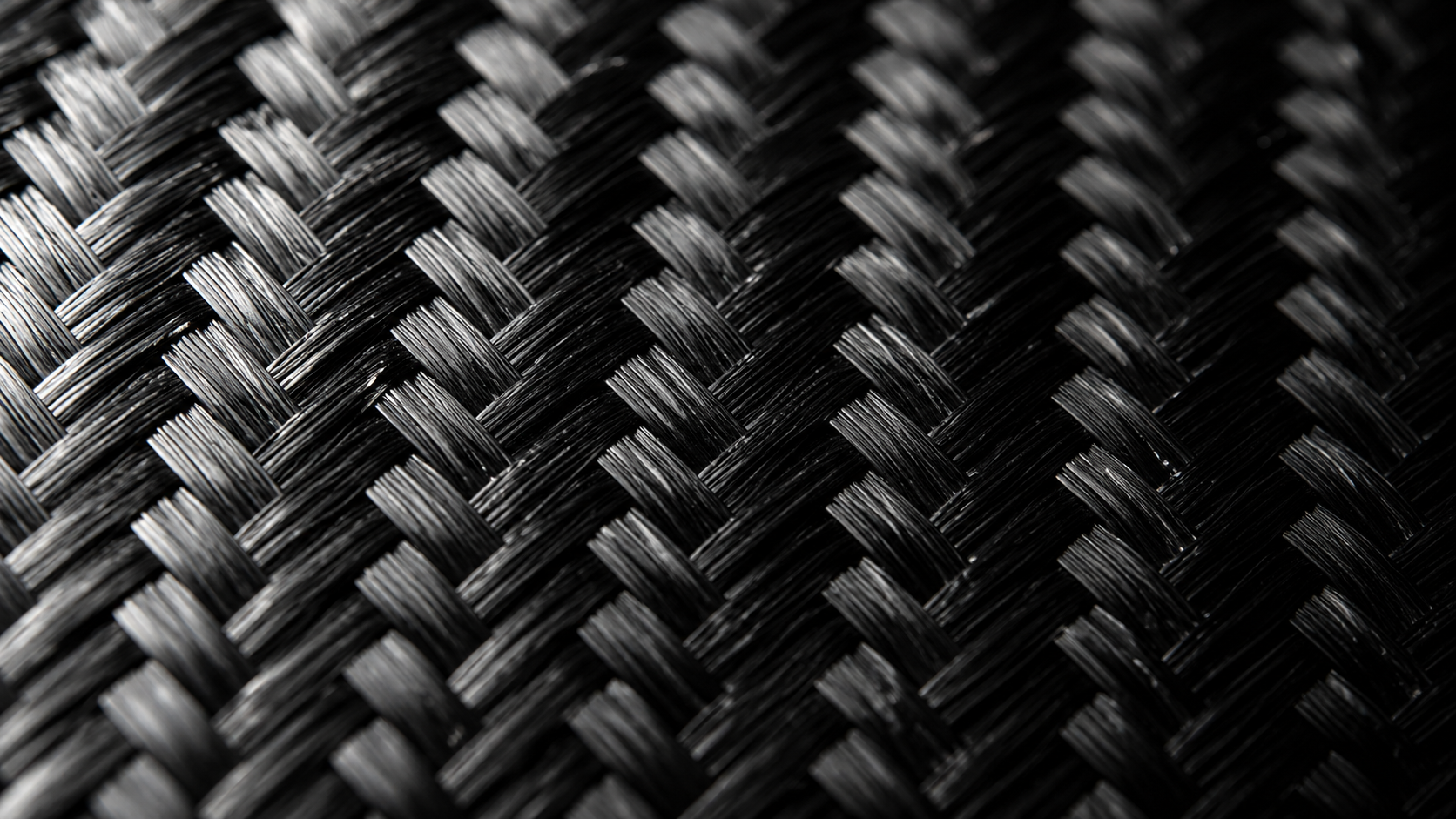 Extreme macro close-up of carbon fibre weave pattern showing the cross-hatch basket weave texture with glossy resin finish