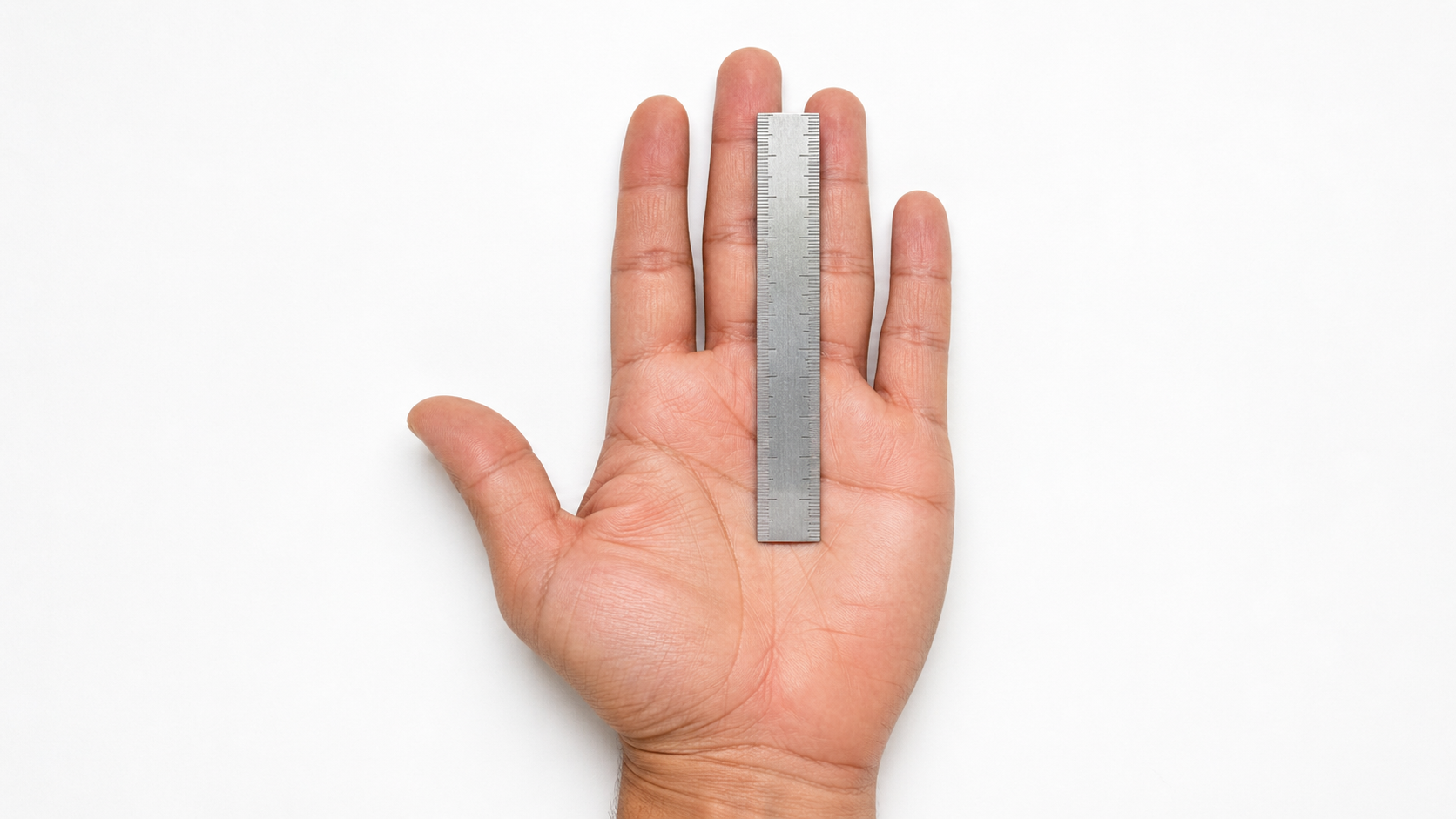Open palm with a silver ruler measuring from the middle palm crease to the ring finger tip on a white background